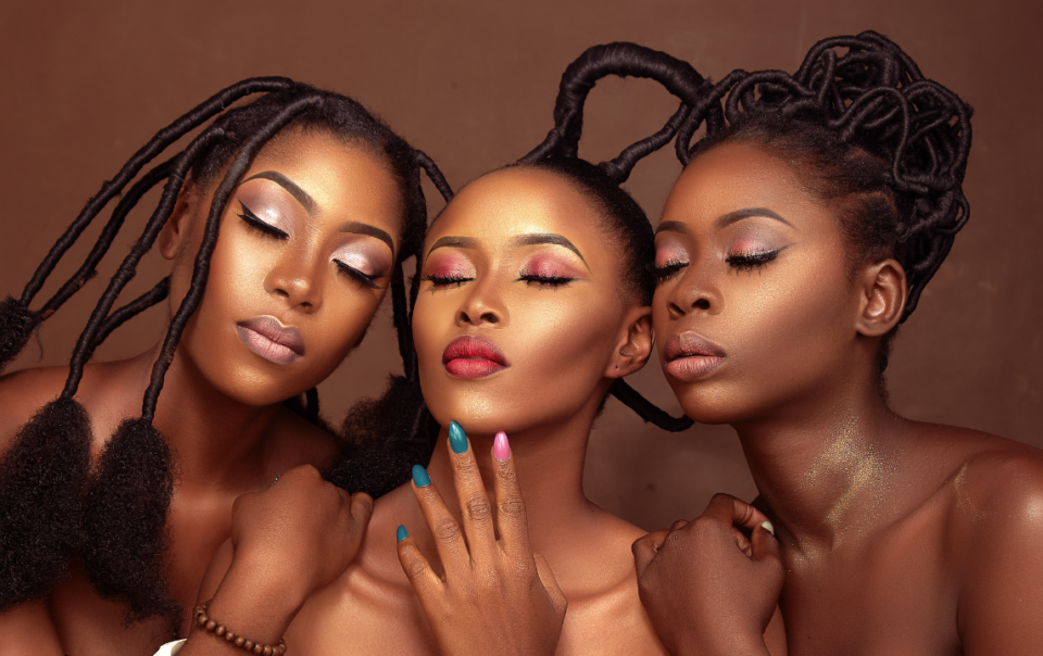 Three luminous black women leaning towards each other with their eyes closed